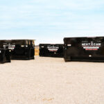 Array of large black Next Can dumpsters lined up on a gravel lot, signifying robust options for dumpster rental in Marion, Ohio.