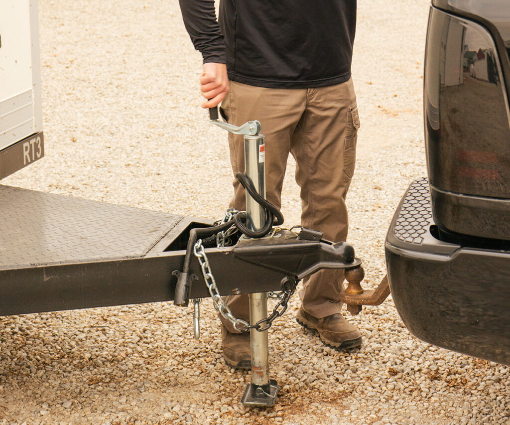 A man securing a Next Can refrigerated trailer to a pickup truck, illustrating easy setup for refrigerated trailer rentals in Marion.