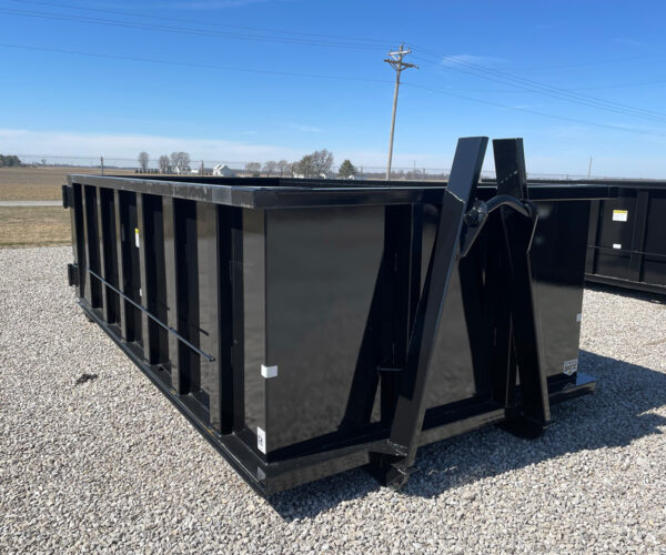 Side view of a black Next Can 15-yard dumpster on a gravel lot, showcasing the open hinge mechanism and yellow caution stickers, ideal for dumpster rental services in Marion, Ohio.