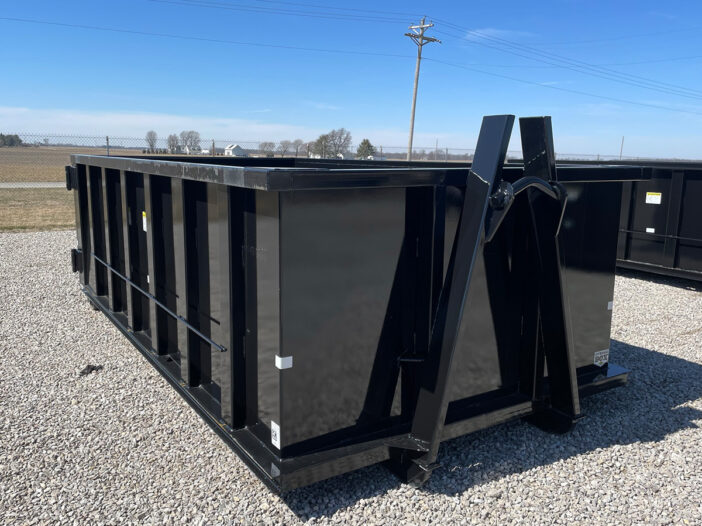 Black roll-off dumpster placed on a gravel surface in an open lot in Marion, Ohio.