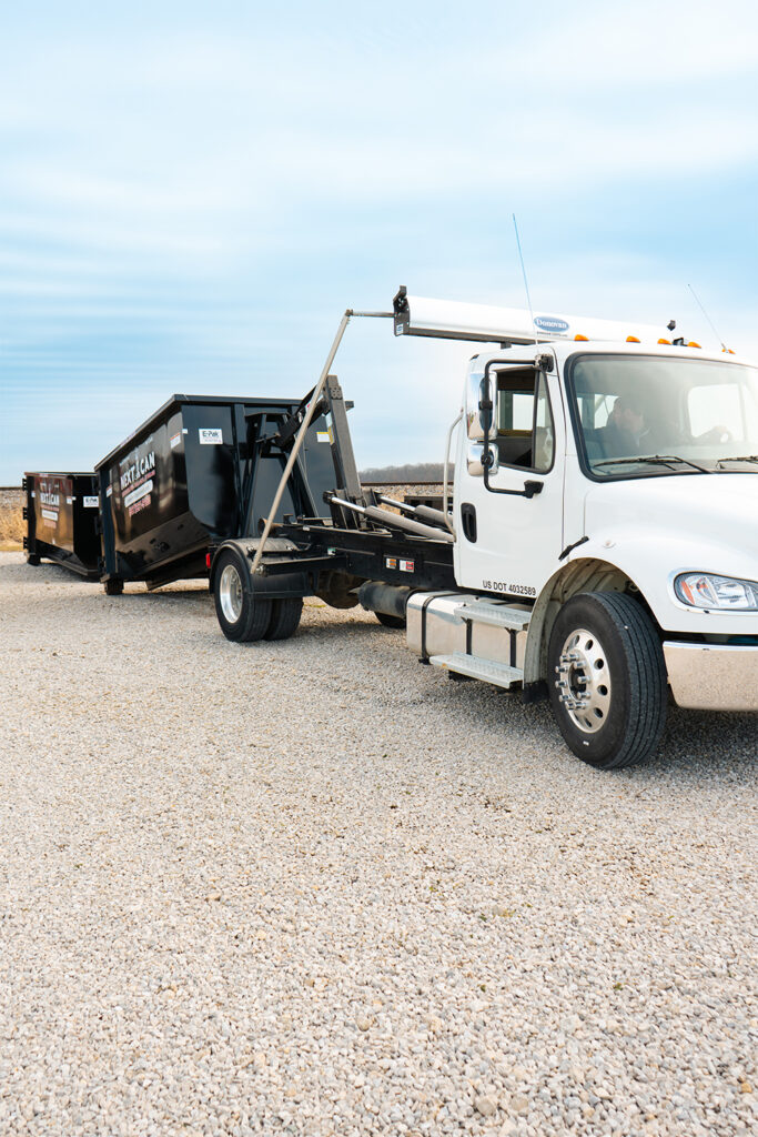 A white Next Can roll-off dumpster truck 