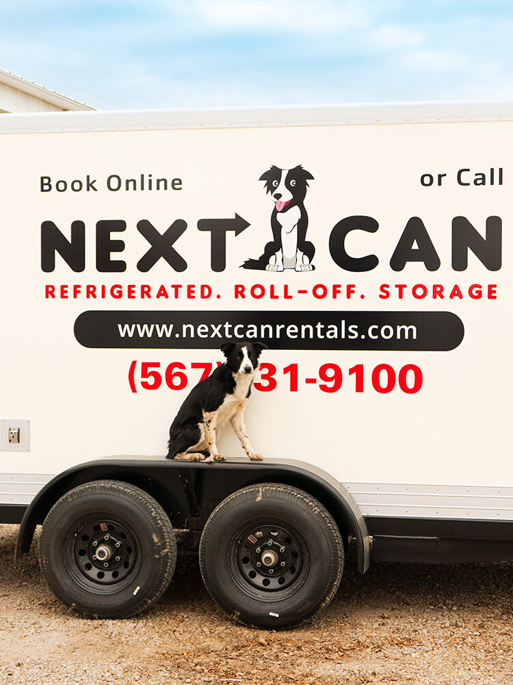 Dog sitting on wheel well of Next Can trailer.