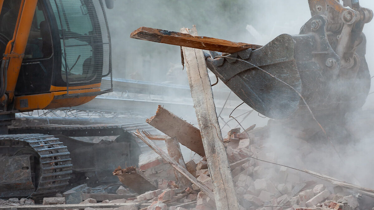 Excavator clearing wood and rubble during construction debris disposal.