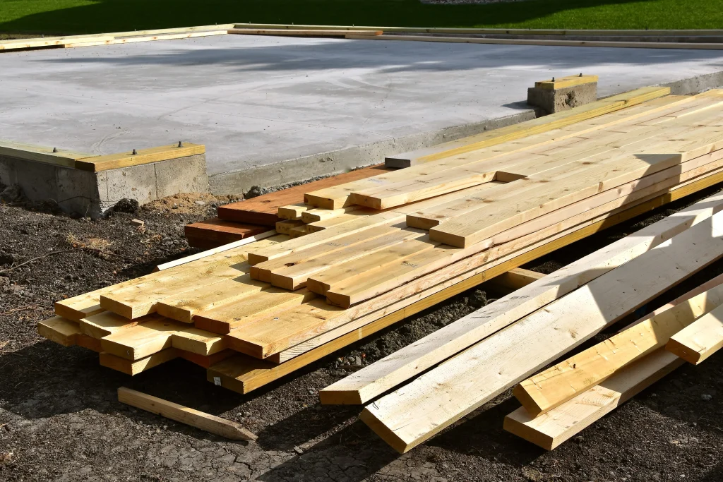 Lumber and construction materials stacked near a concrete project site